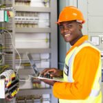 african electrical worker using laptop computer checking transformer
